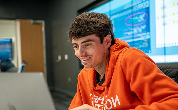 数据分析专业的学生微笑着看着笔记本电脑